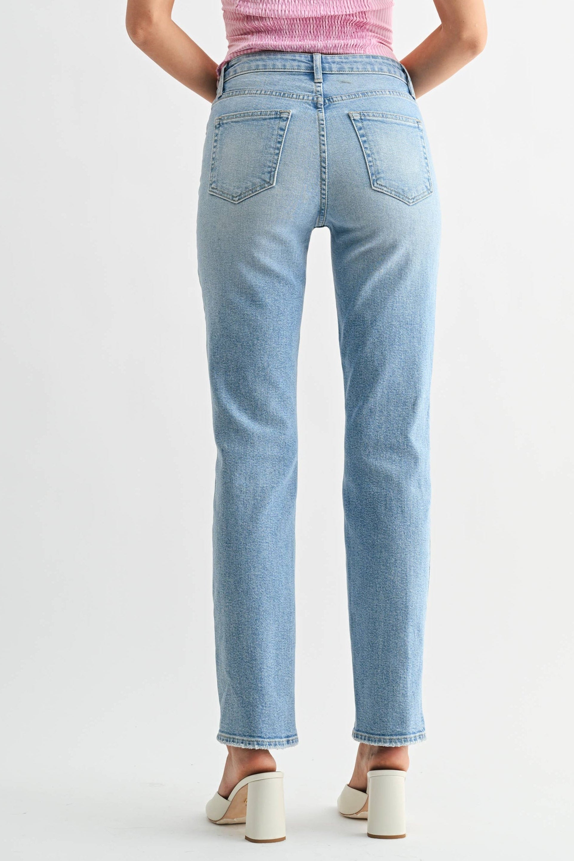 Woman wearing a pink top and light blue jeans on a white background