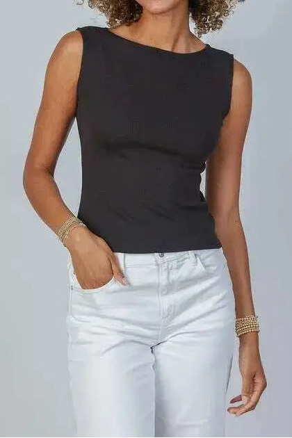 Woman wearing a black sleeveless top and light blue jeans against a plain background