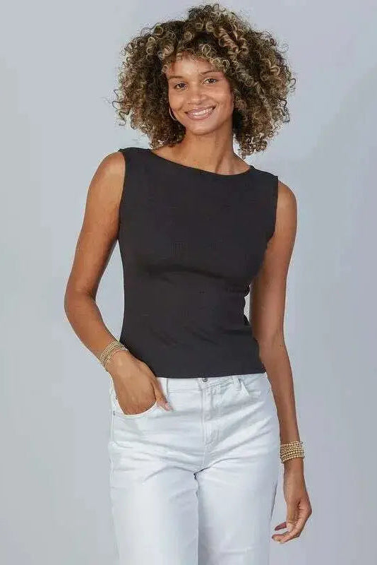 Woman wearing a black sleeveless top and light blue jeans against a plain background