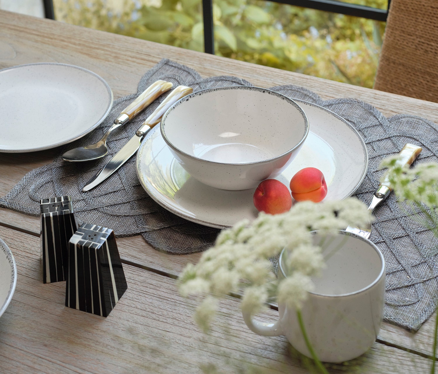 Dining table setting with plates, bowls, and cutlery on a wooden surface.
