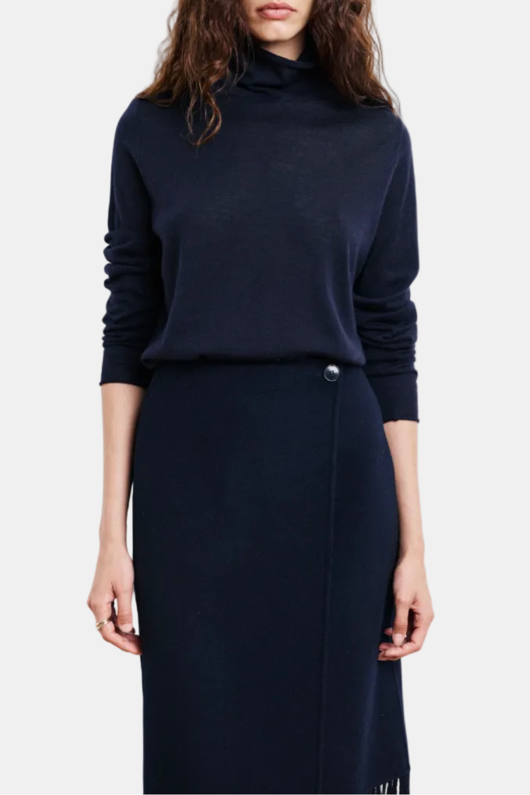 Woman wearing a navy blue turtleneck sweater and skirt on a white background