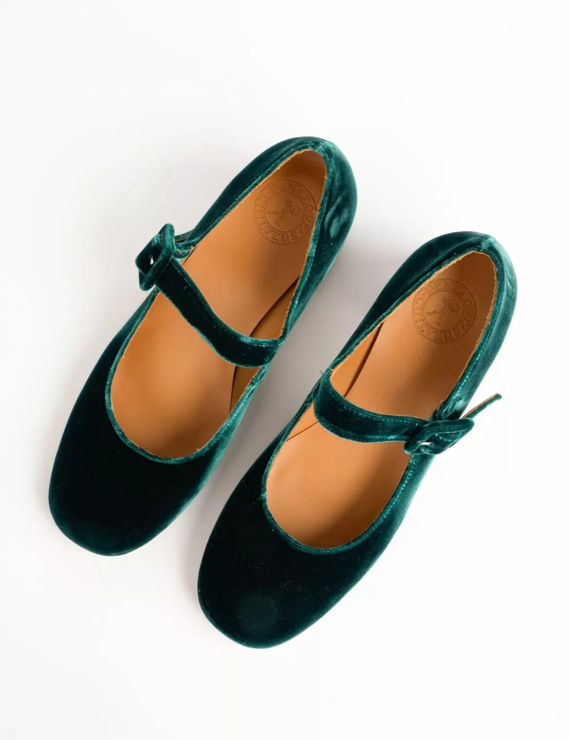 Pair of green velvet shoes with brown soles on a white background