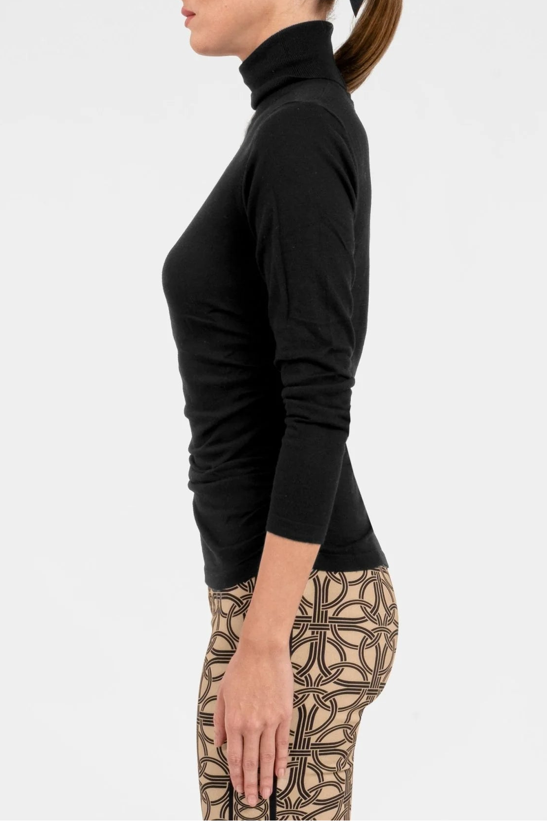 Woman wearing a black turtleneck and patterned pants on a white background