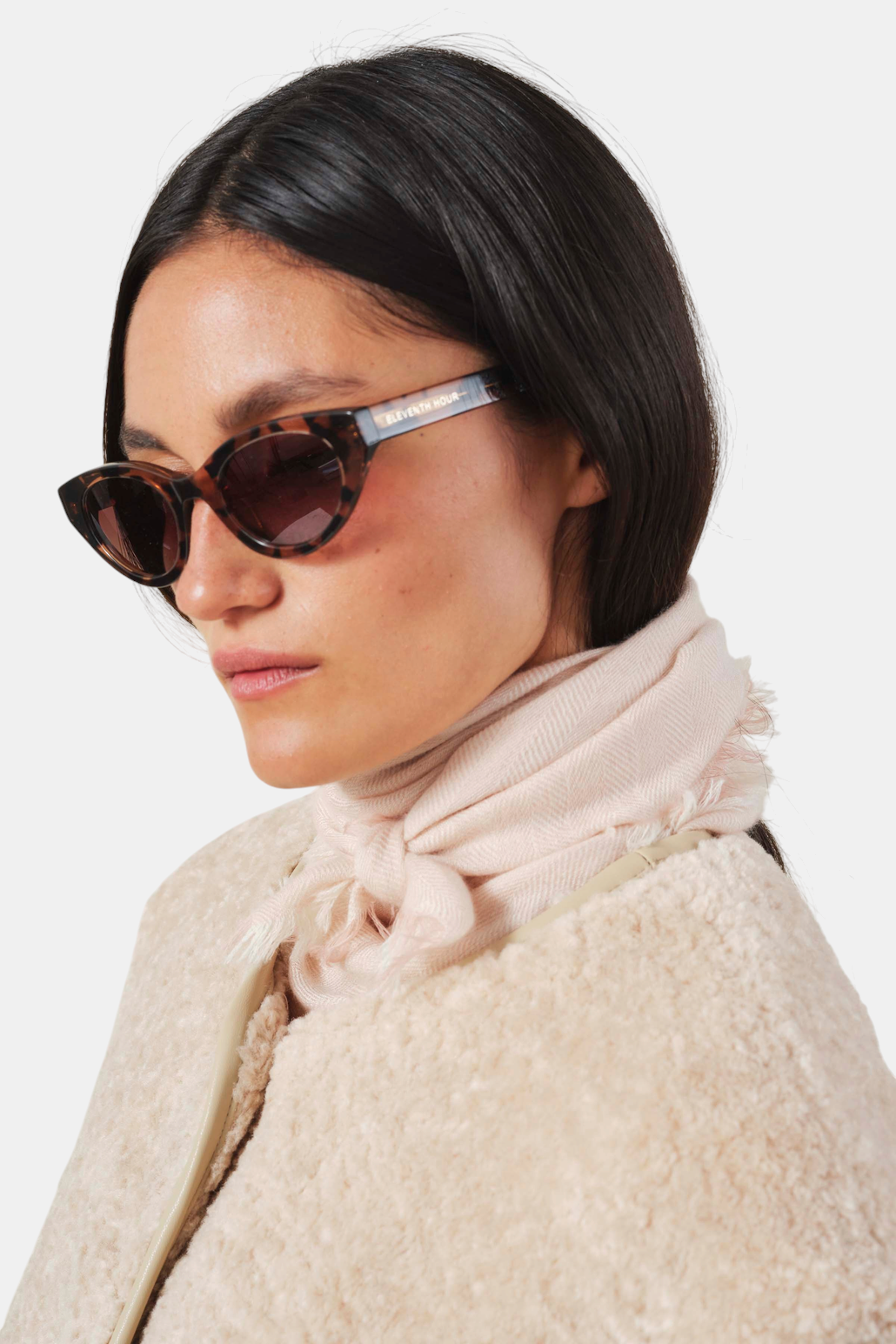 The Copper Shed light pink cashmere scarf with herringbone pattern and frayed edges worn knotted around the neck.
