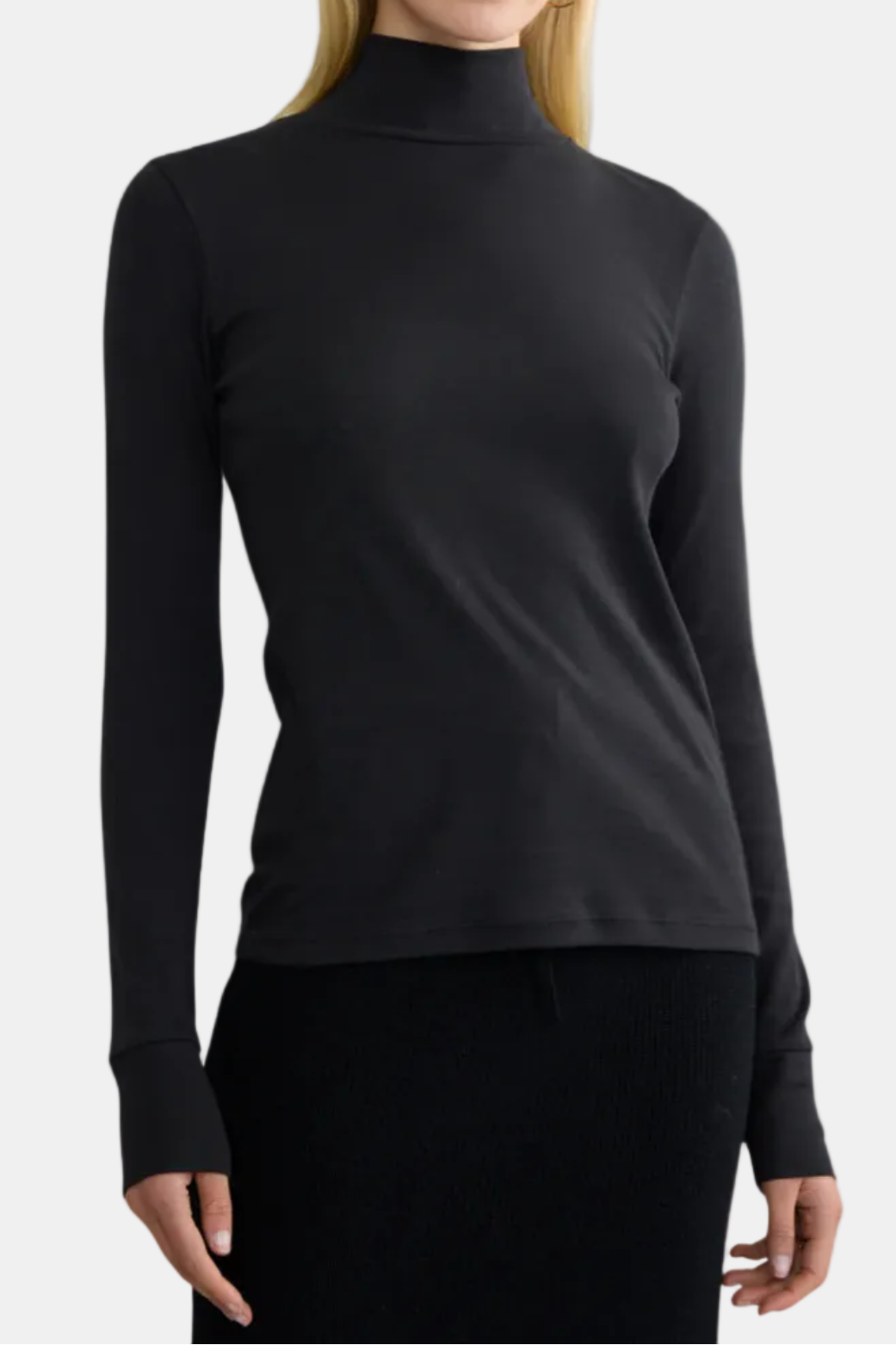 A woman wearing a black long-sleeve turtleneck top with ribbed texture.