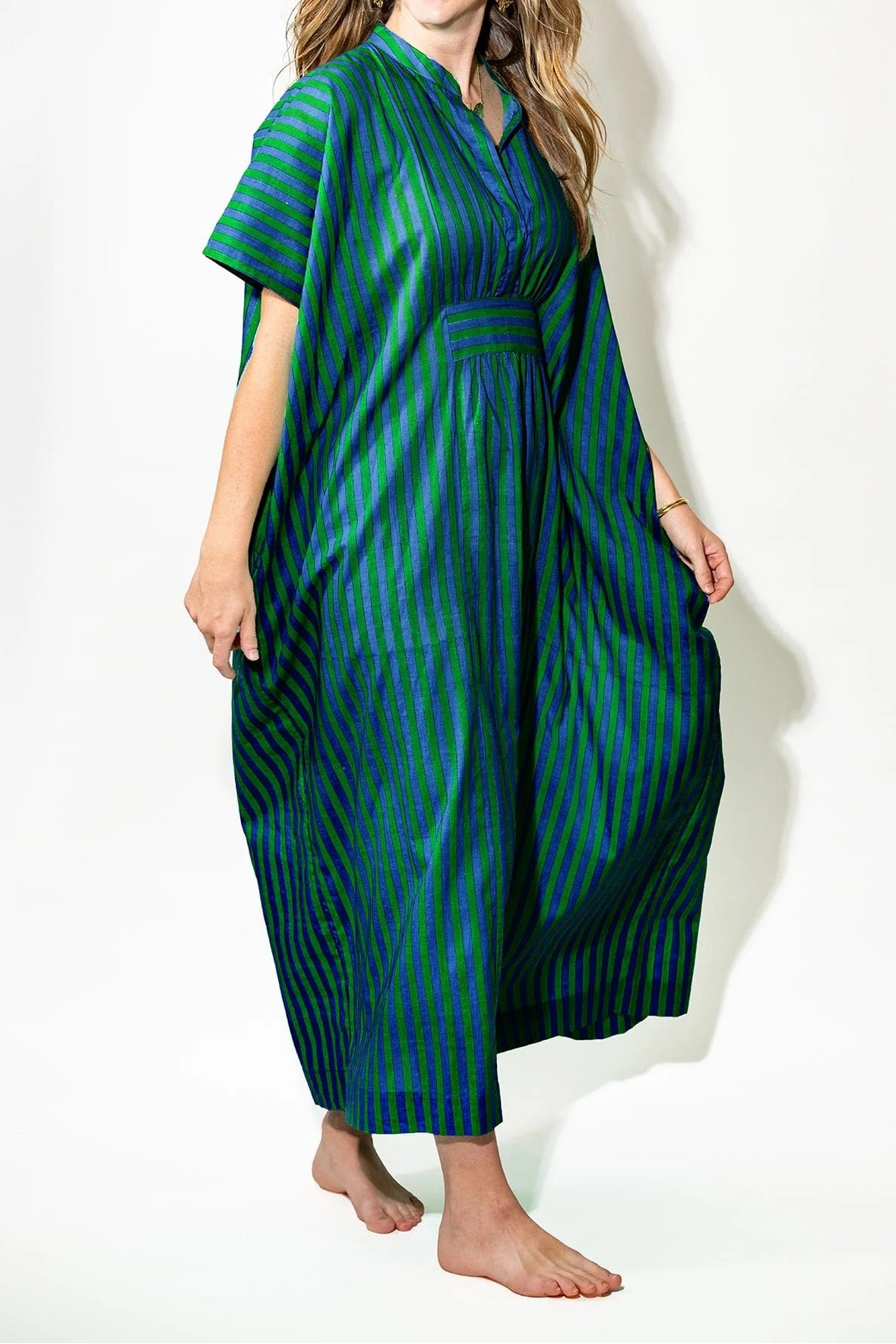 Woman wearing a green and blue striped dress on a white background