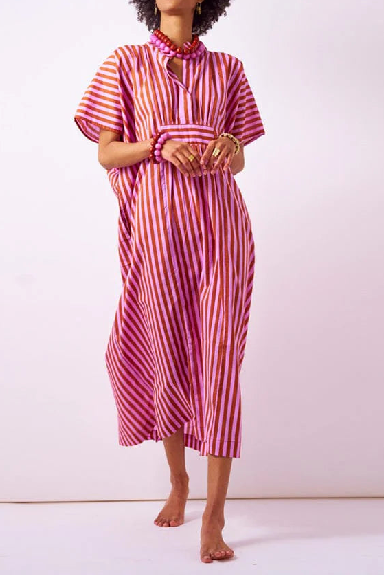 Woman wearing a pink and orange striped dress against a white background