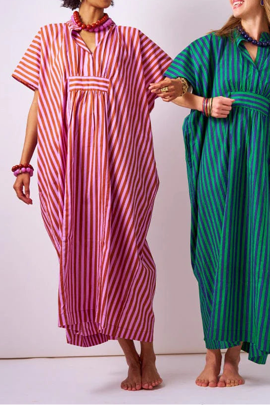 Two women wearing colorful striped kaftans against a white background