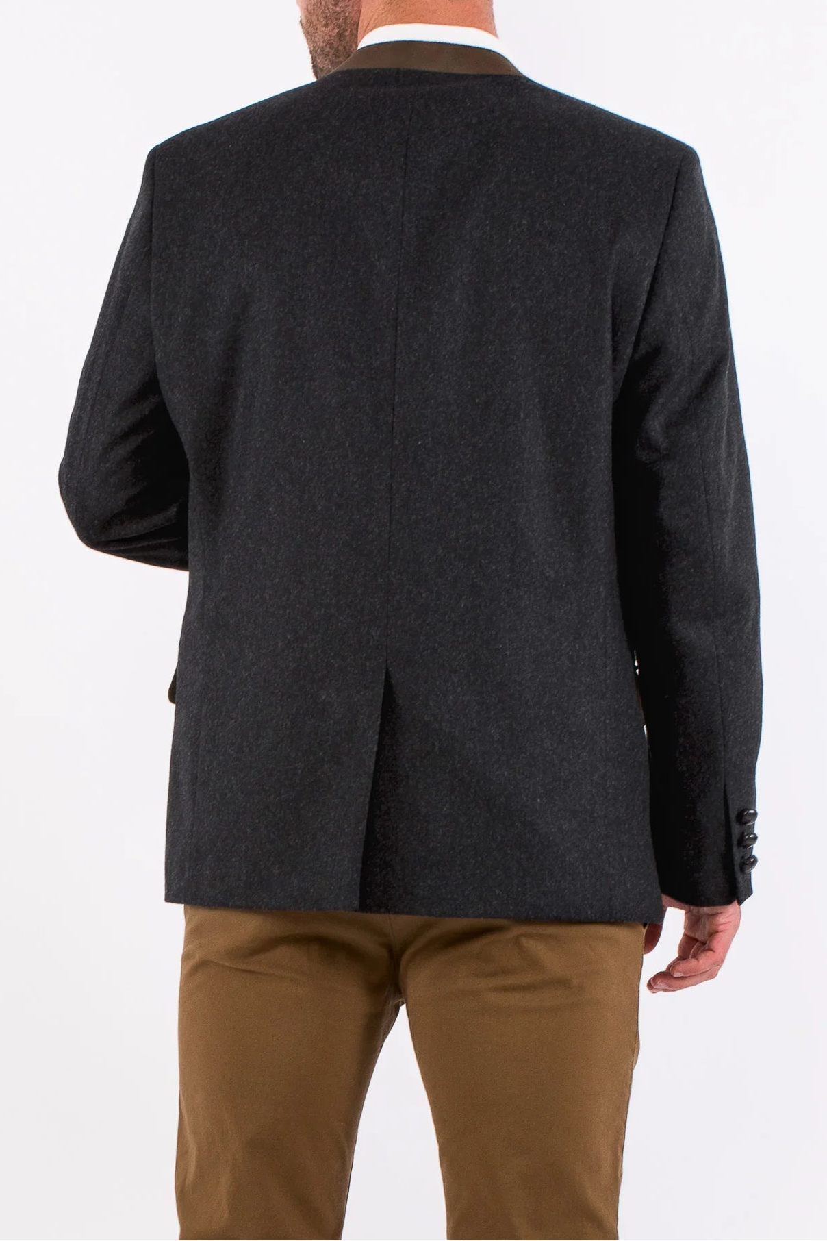 Man wearing a dark gray blazer and brown pants on a white background