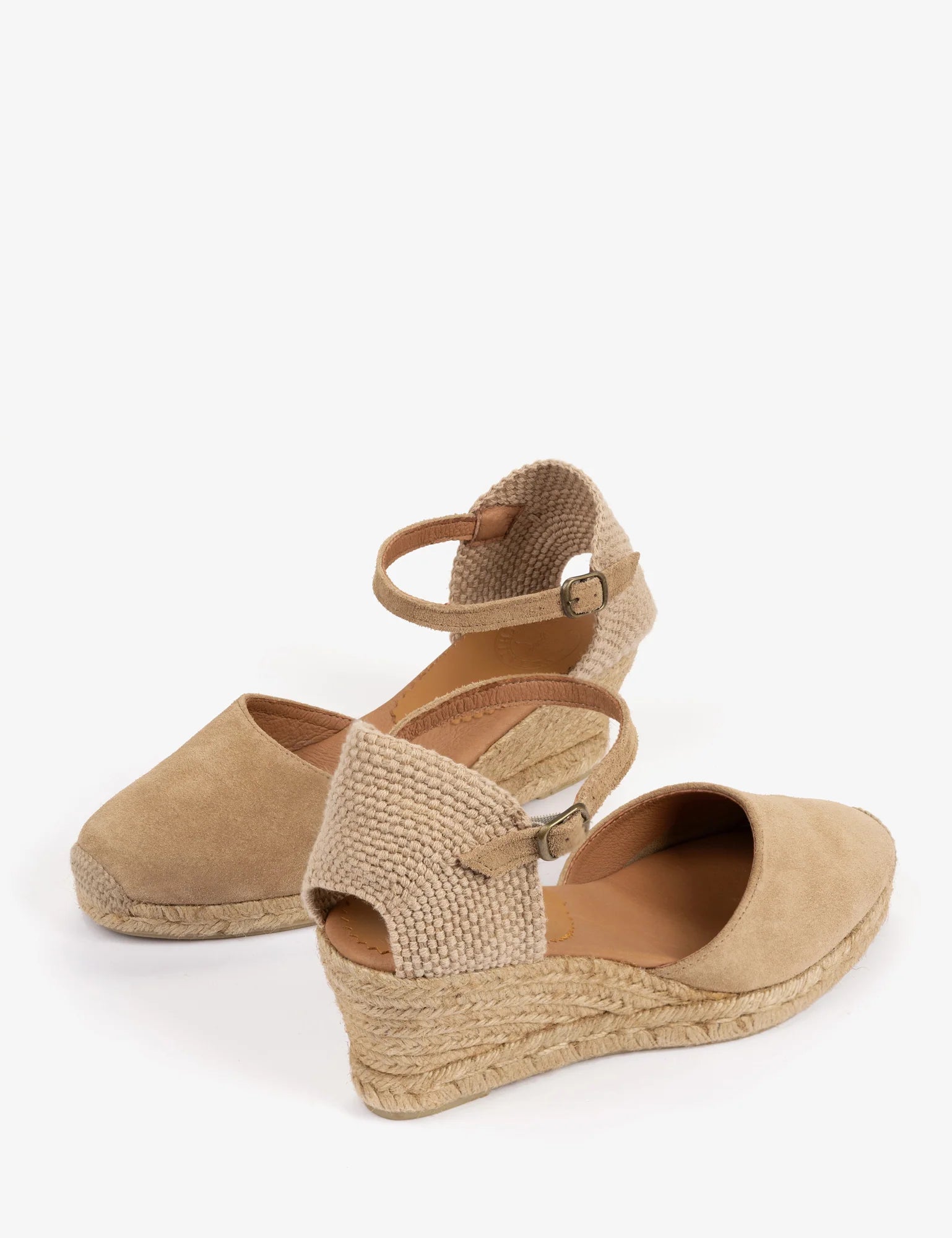 A pair of women's wedge sandals in beige suede and braided jute, featuring an ankle strap with a small buckle, shown on a plain white background.