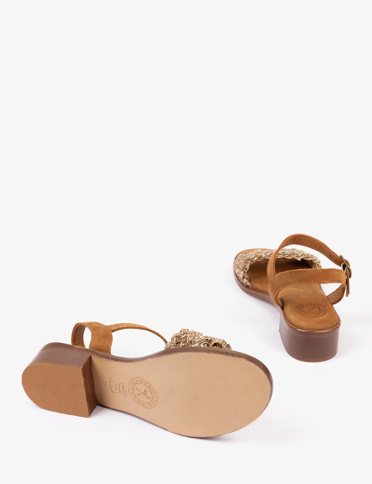 Pair of brown sandals with gold glittery straps on a white background