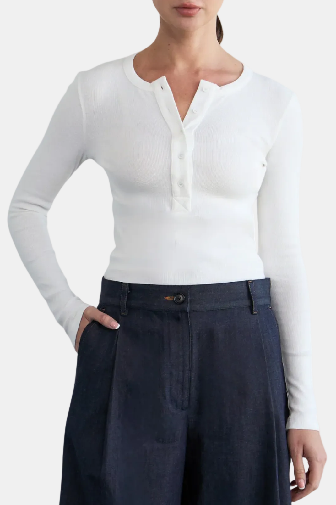 Woman wearing a white long-sleeve shirt and dark pants on a white background