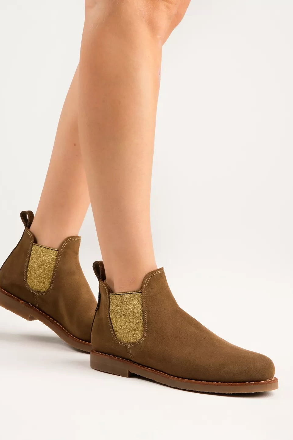 Brown suede Chelsea boots worn by a person on a white background