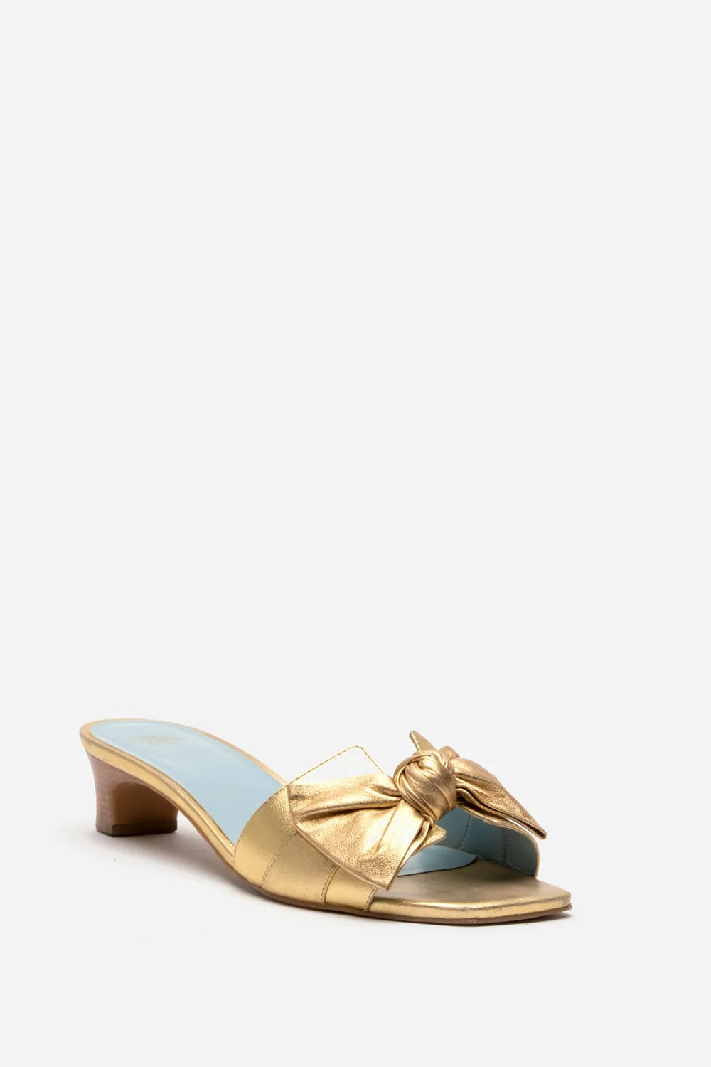 A single metallic gold mule sandal with a low block heel and a large decorative bow on the toe strap, shown against a plain light gray background.