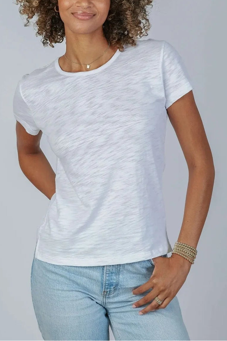 Woman wearing a white t-shirt and light blue jeans against a plain background