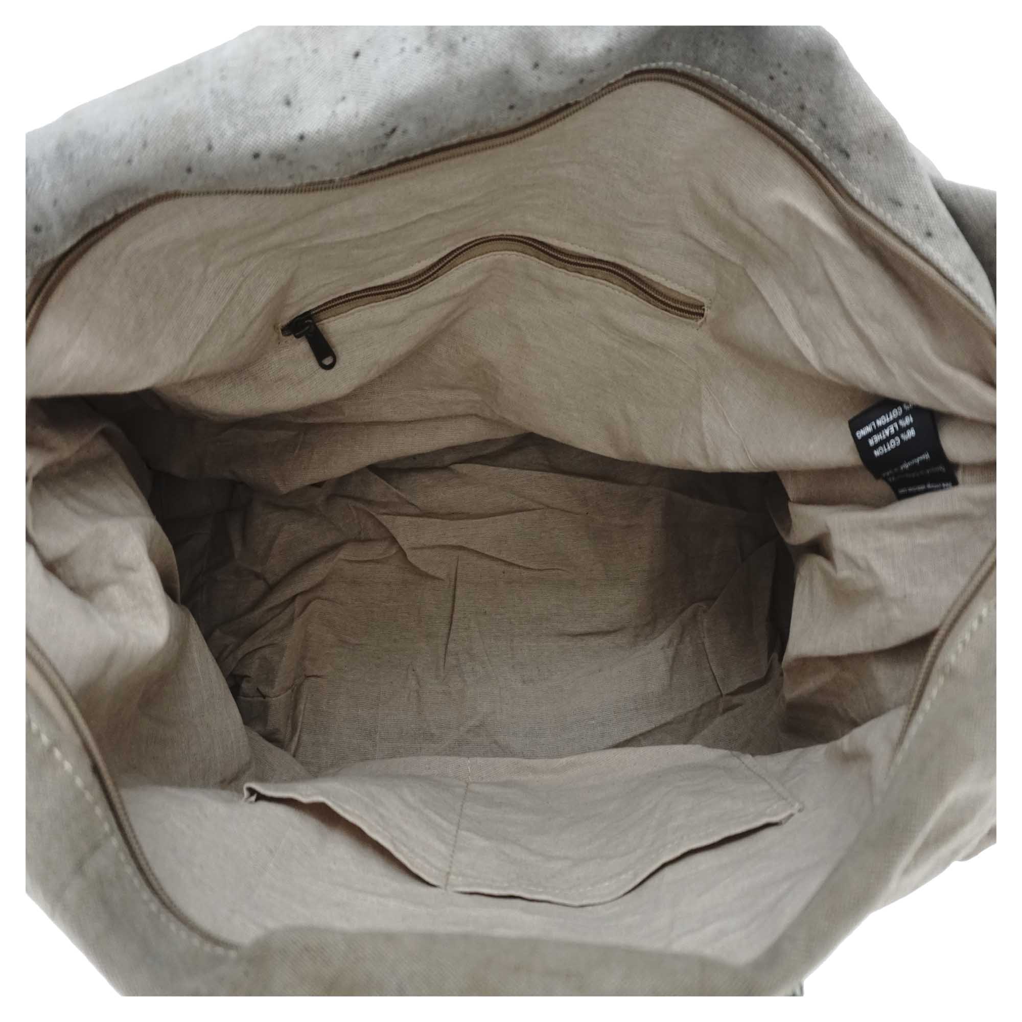 The interior of a beige canvas tote bag, showing a zippered pocket on the inner lining and a black fabric brand tag on the right side.