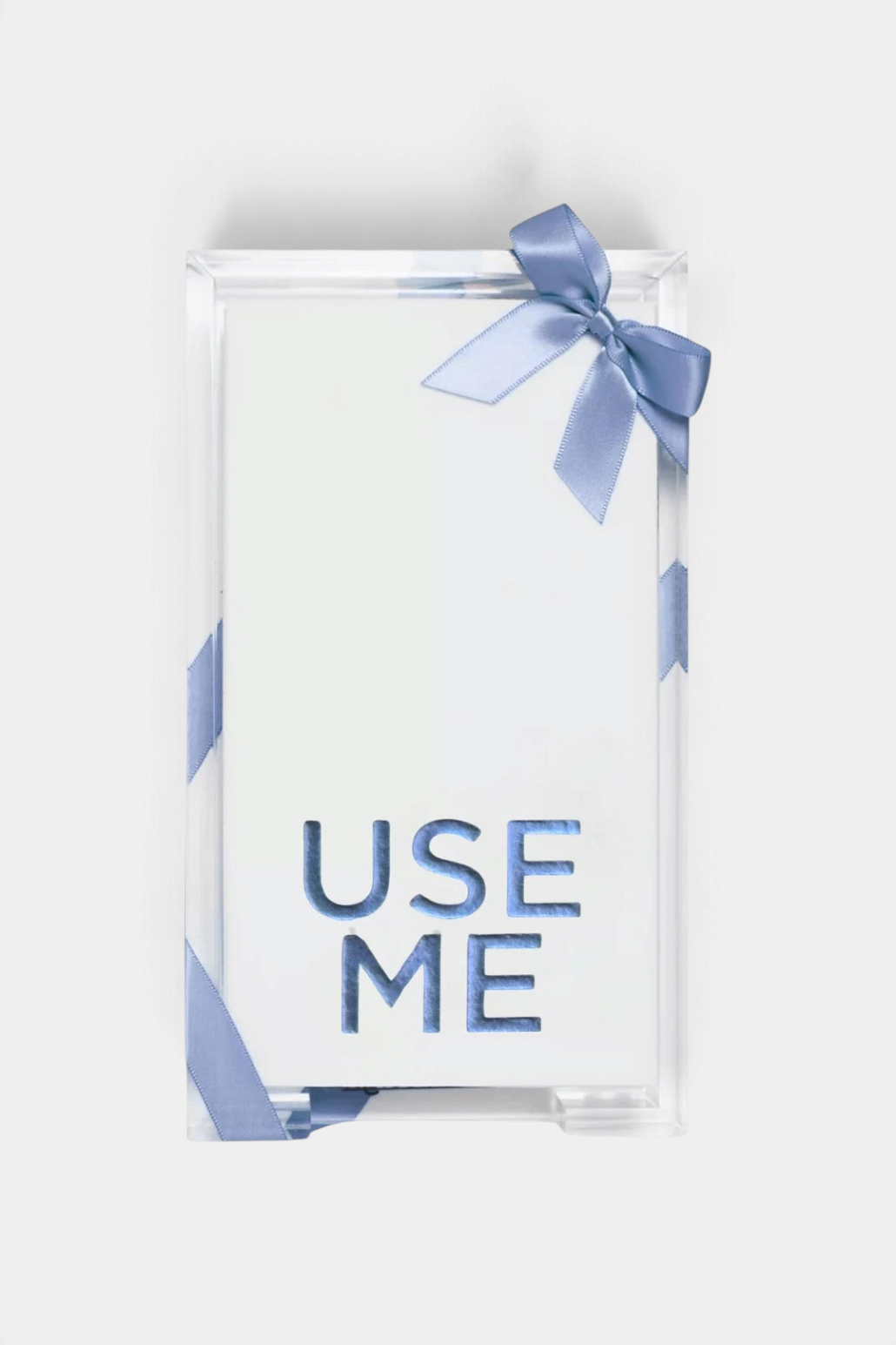 The Copper Shed clear acrylic tray holding white guest towels with blue foil embossed Use Me text and a blue ribbon.