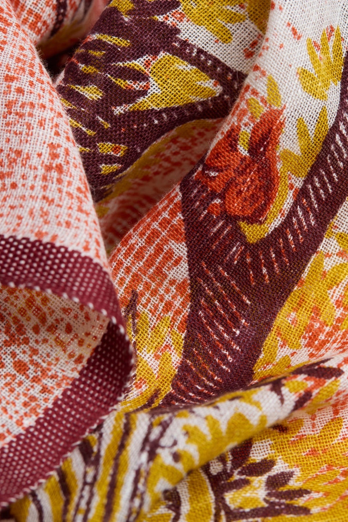 The Copper Shed Ambroise scarf featuring a hand-printed floral pattern in shades of maroon, orange, and yellow on linen