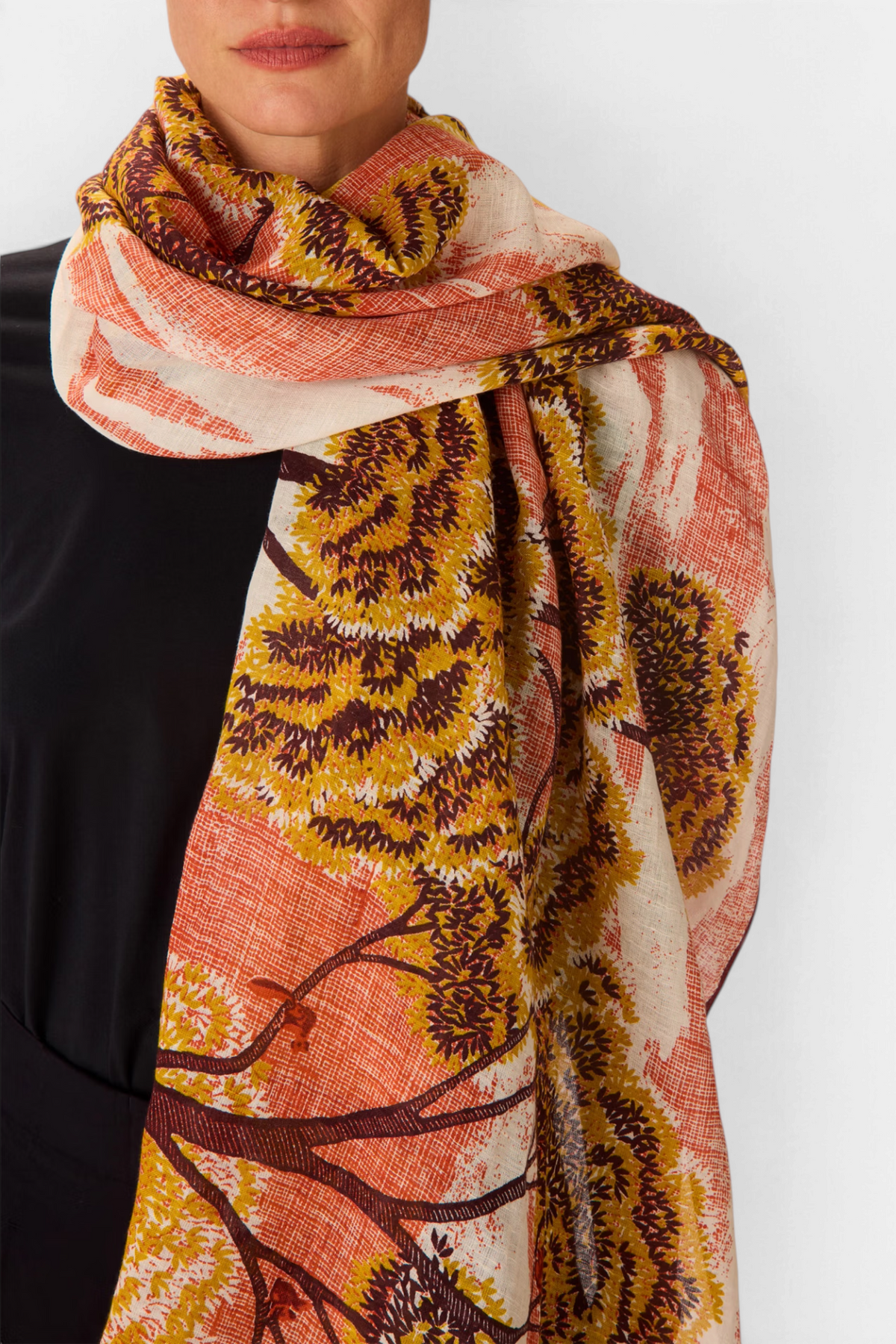 The Copper Shed Ambroise linen and cotton scarf featuring a hand-printed orange and yellow tree landscape pattern.