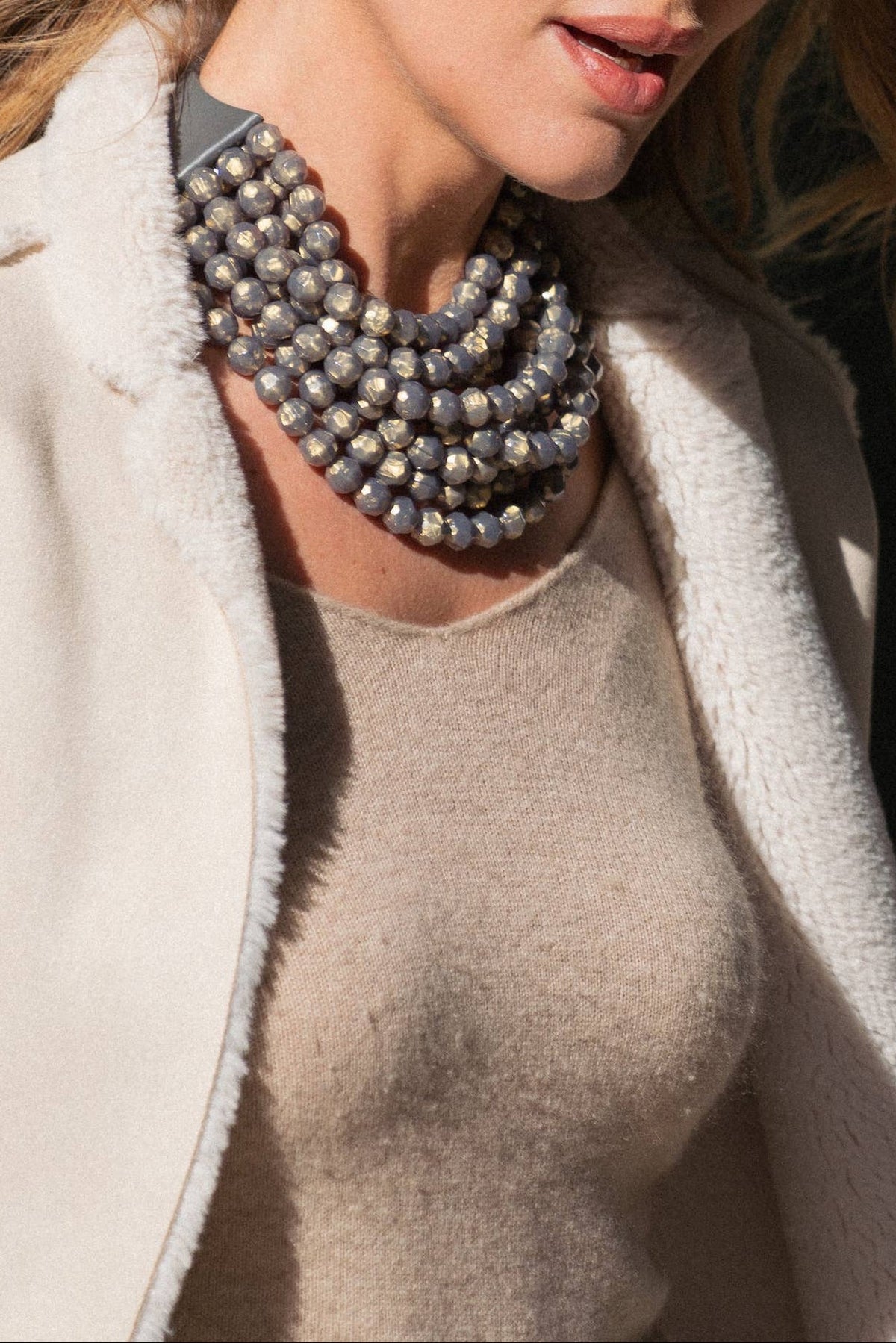 The Copper Shed Bella Grigio multi-strand resin bead necklace with leather collar worn over a beige sweater