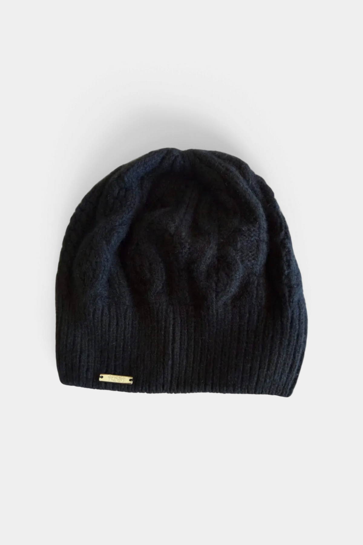 The Copper Shed black cable knit beanie made from a soft cashmere and merino wool blend with a small gold logo tag.