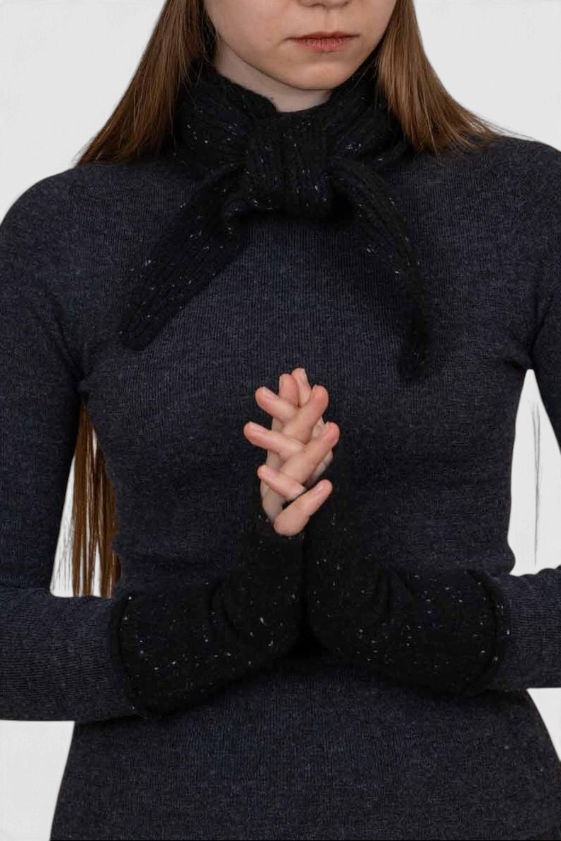The Copper Shed black organic cashmere neck scarf with subtle colourful flecks worn by a woman.