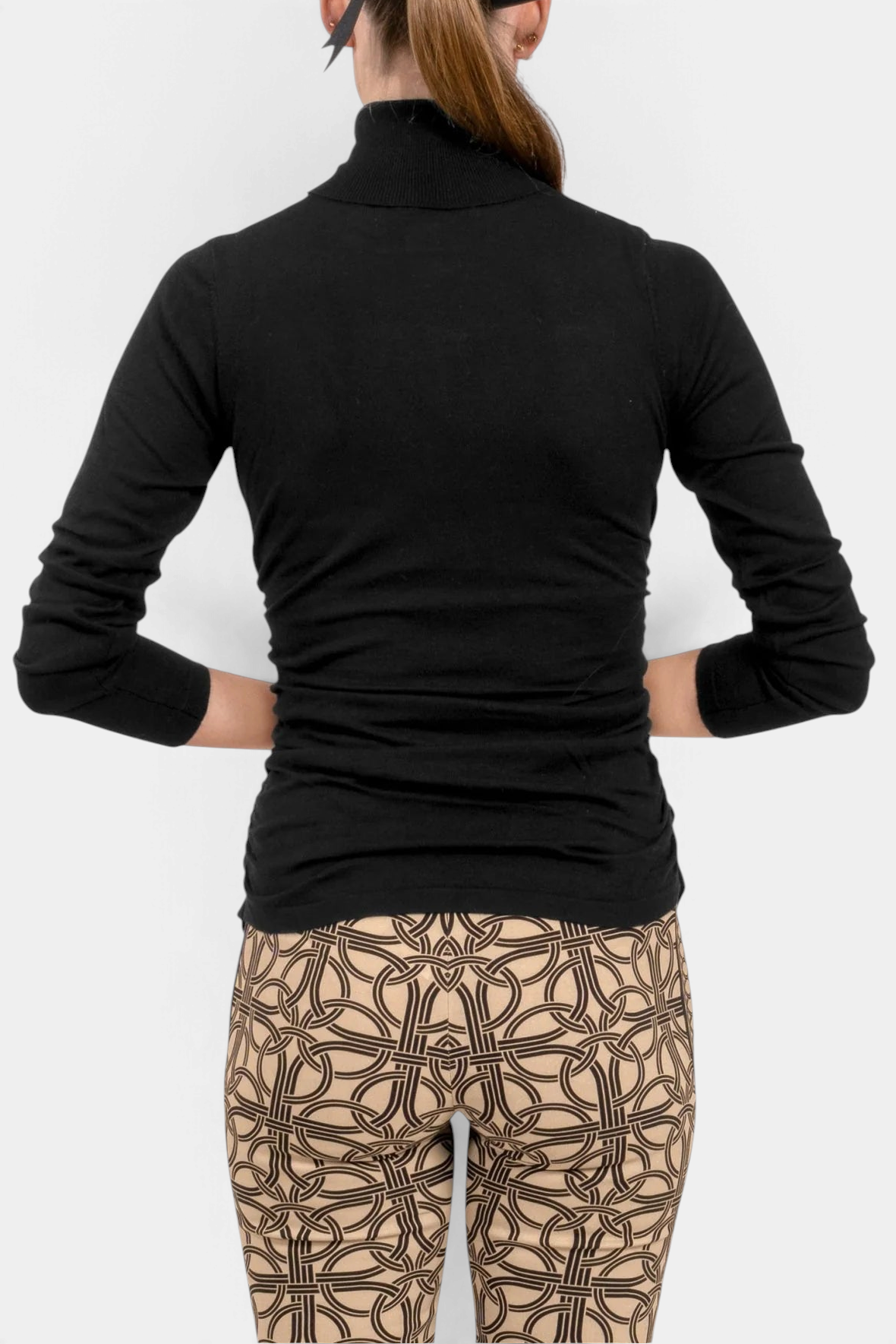 The Copper Shed black cashmere turtleneck sweater worn by a woman, showing a fitted long-sleeve back view.