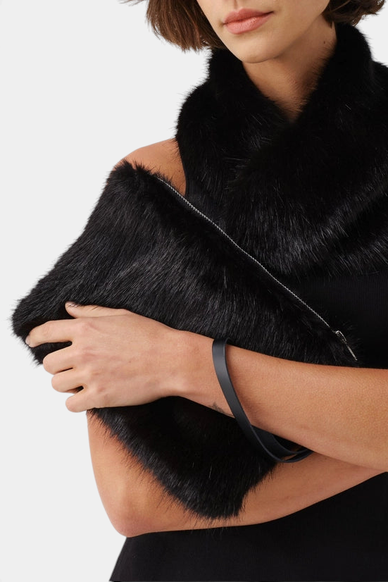 The Copper Shed black faux fur clutch bag with a detachable leather wrist strap held by a woman in a black dress.