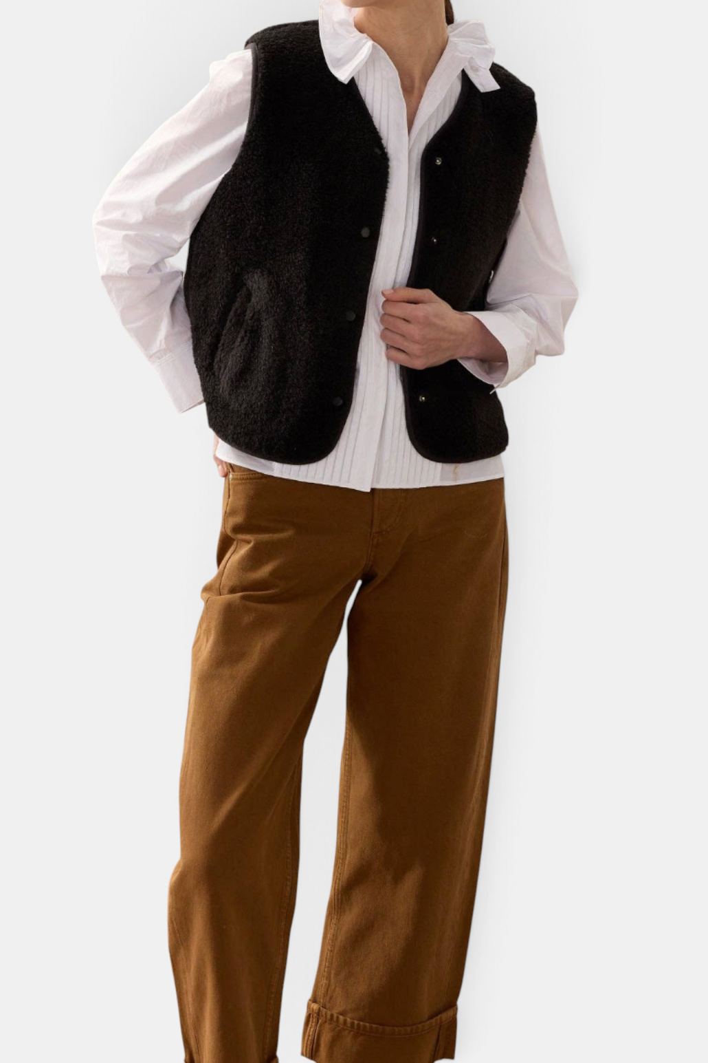 The Copper Shed black faux sheepskin gilet with popper fastening and front pockets worn over a white shirt