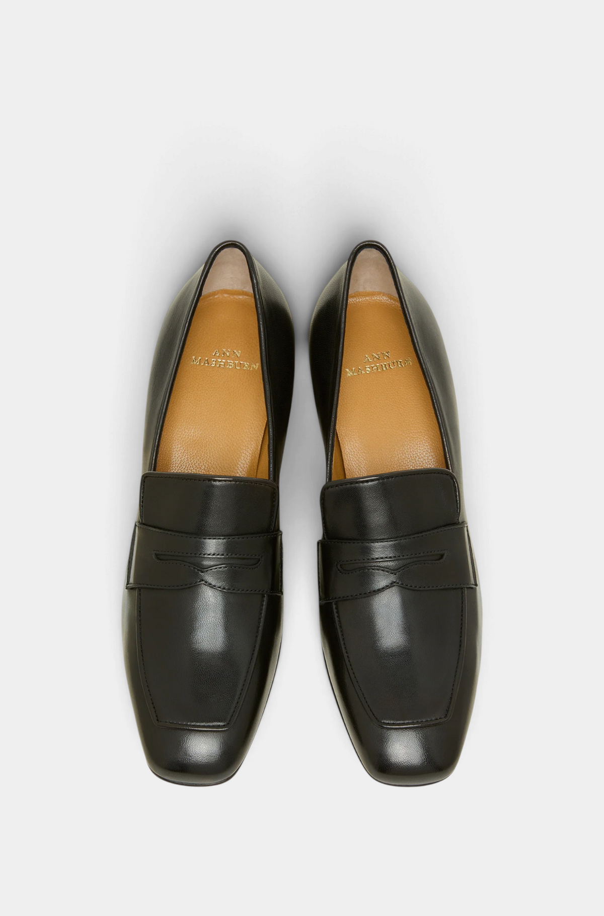 The Copper Shed black leather heeled loafers with a traditional penny slot design, top-down view.