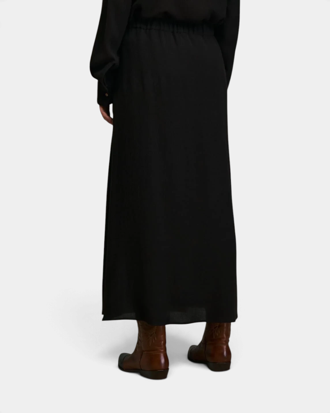 The Copper Shed Diega Jabo black maxi skirt worn with brown leather boots, back view