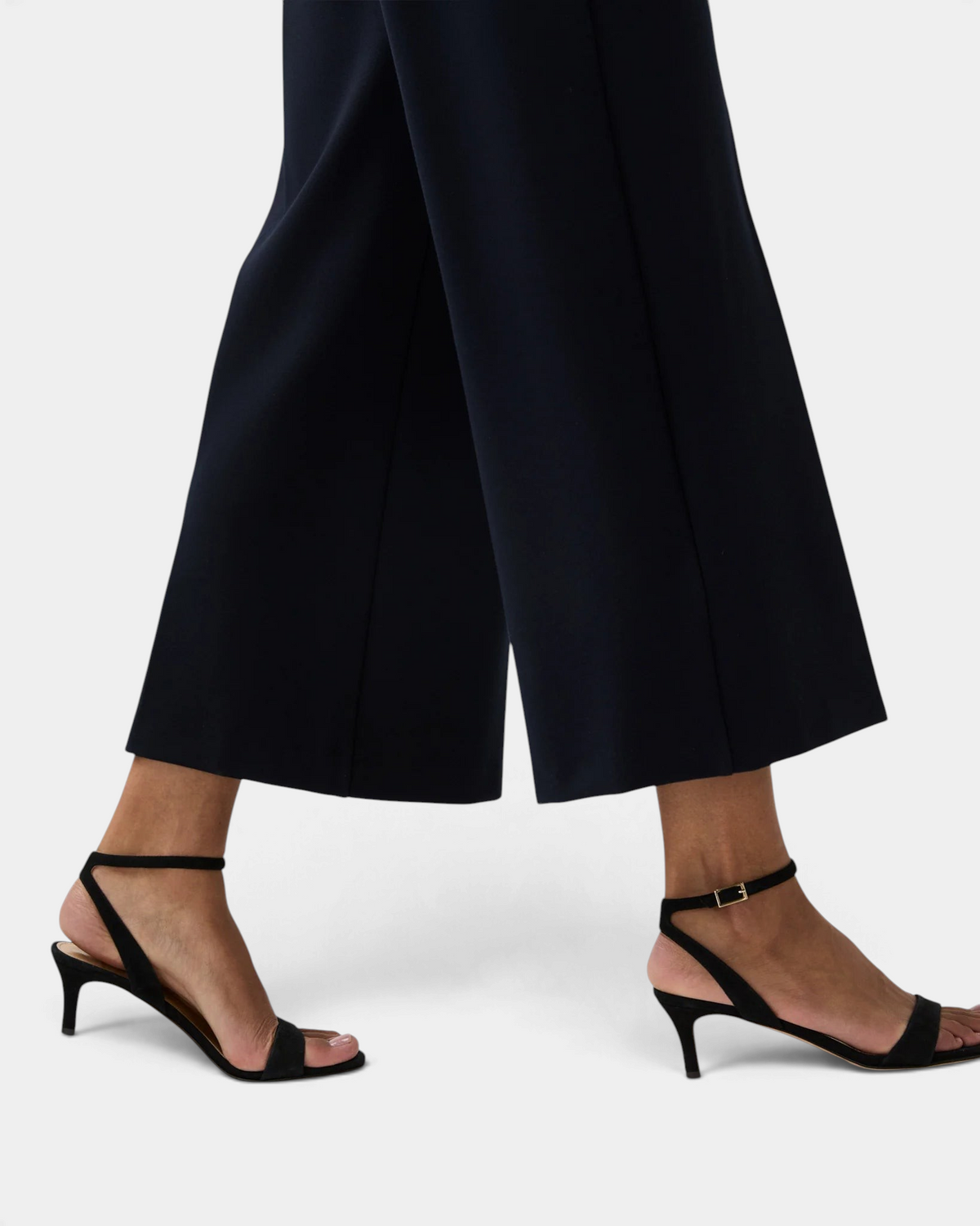 The Copper Shed black Italian calf suede kitten heel sandals with an ankle wrap and buckle closure on a model