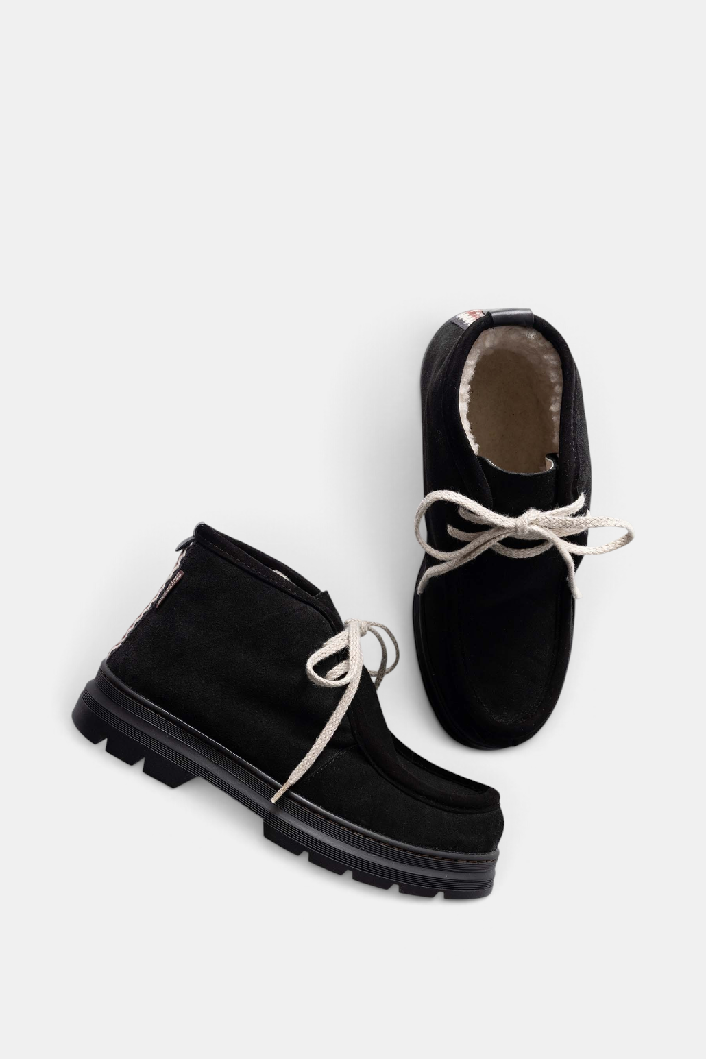 The Copper Shed black split suede shearling-lined boots with ecru laces and folk trim detail on a rubber tread sole.