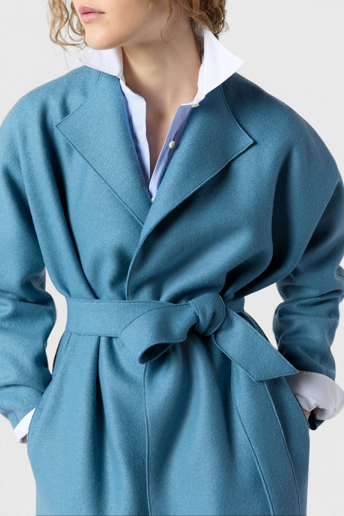 The Copper Shed Kimono Carina coat in blue Italian boiled wool with a belted waist and wide lapels