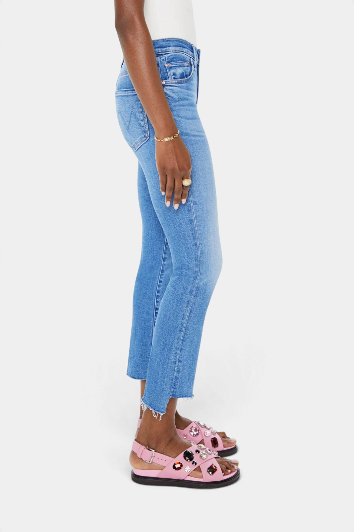 The Copper Shed high-waisted blue denim jeans with a cropped frayed step-hem worn by a model in profile view