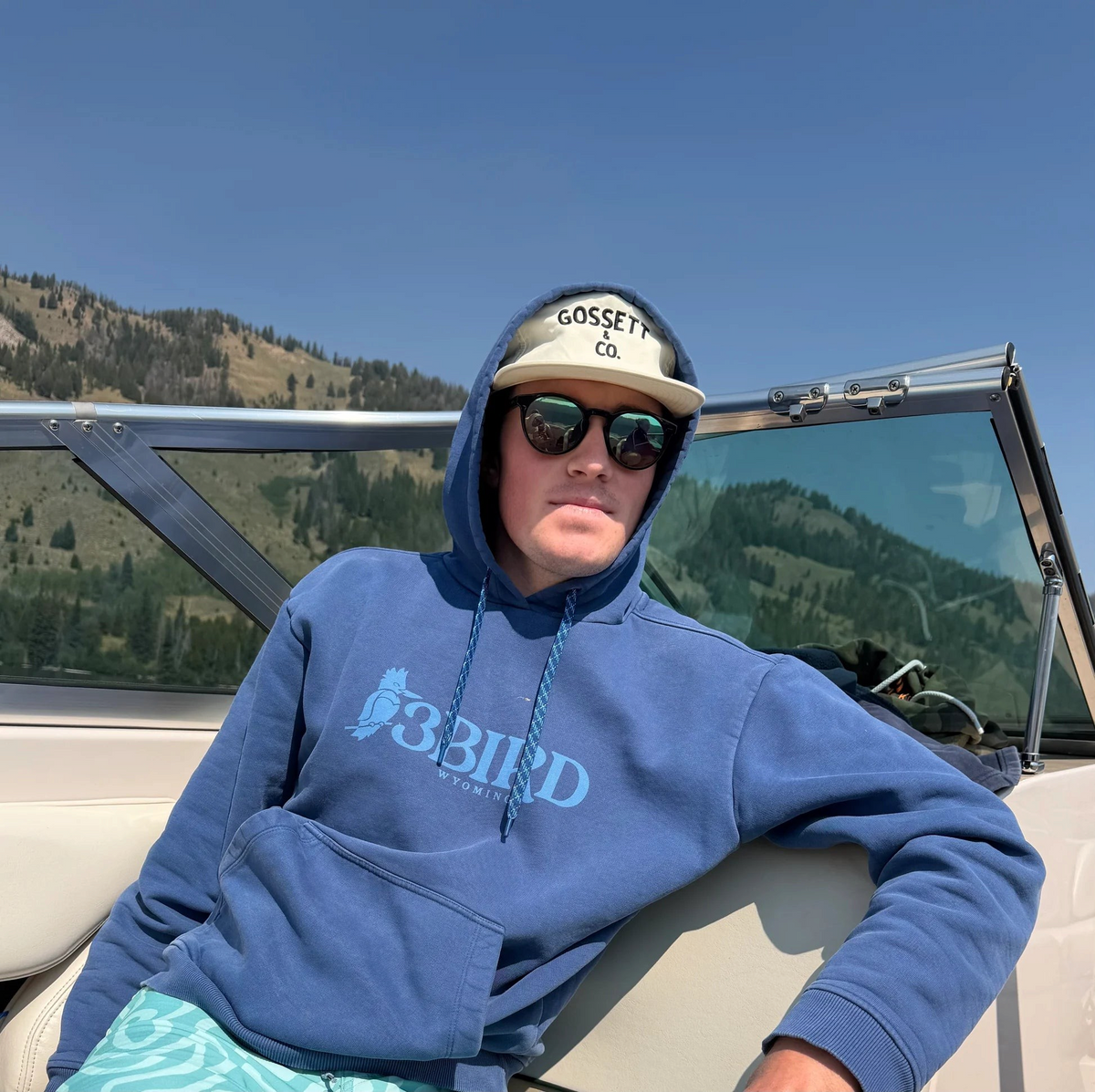 The Copper Shed 3B Heritage Hoodie in blue organic cotton with kangaroo pocket worn by a man on a boat
