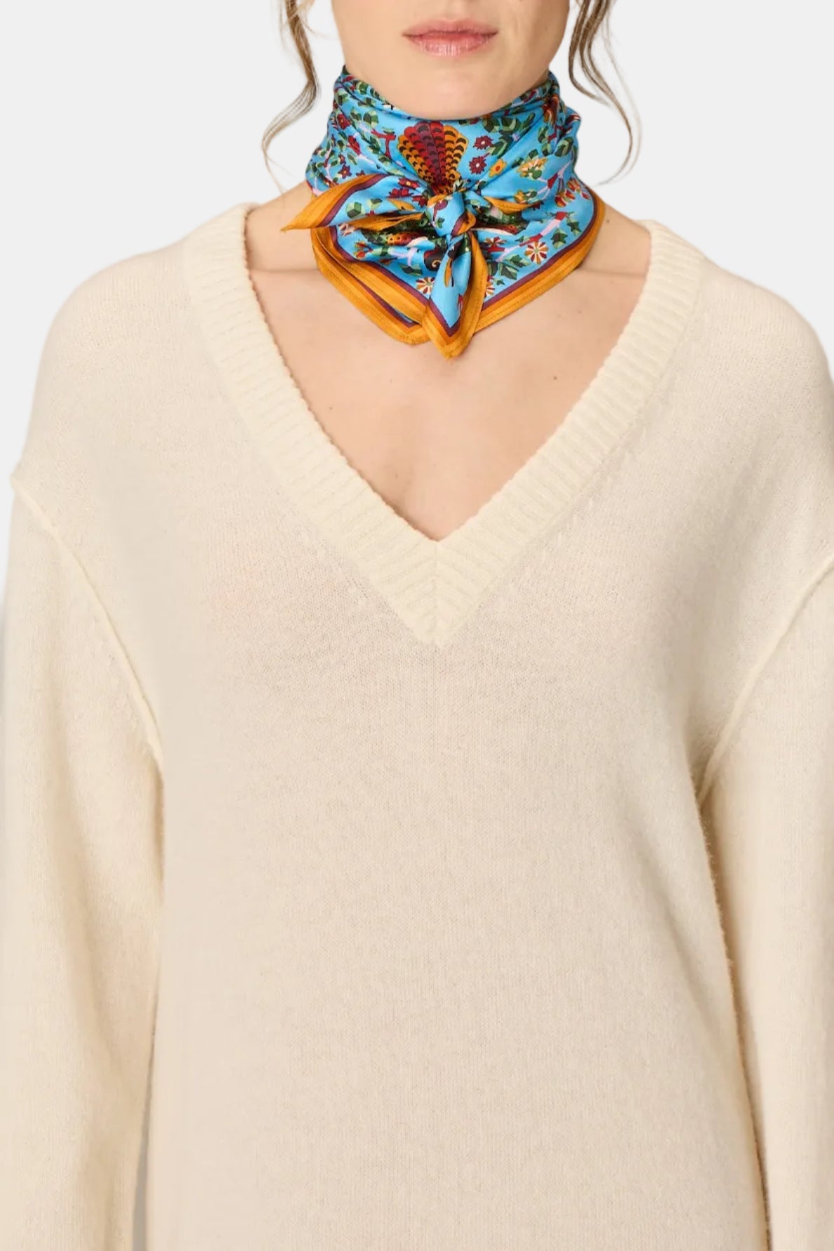 The Copper Shed Square 65 Perrot blue silk scarf with floral bird print worn around a model's neck