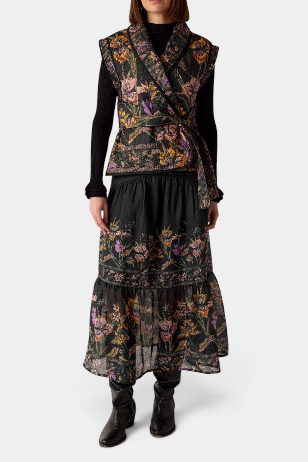 The Copper Shed Bowie vest in black floral quilted cotton with a shawl collar and tie belt worn over a matching skirt