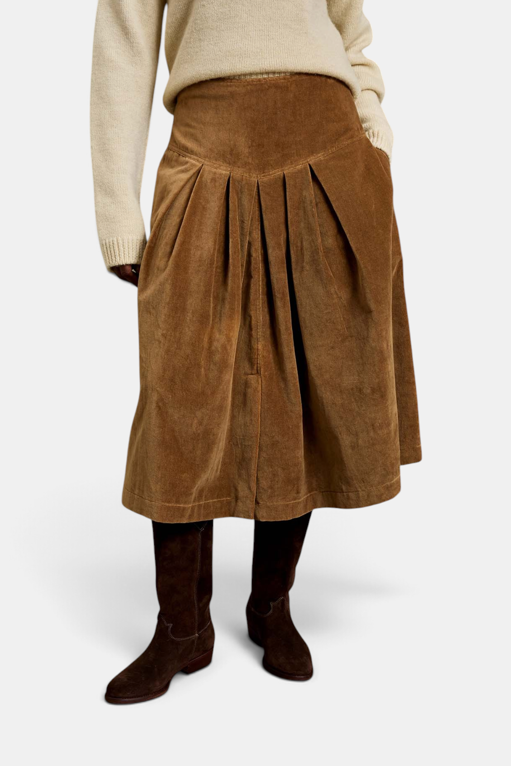 The Copper Shed Lancaster skirt in brown cotton velvet with a pleated silhouette worn with boots and a cream sweater