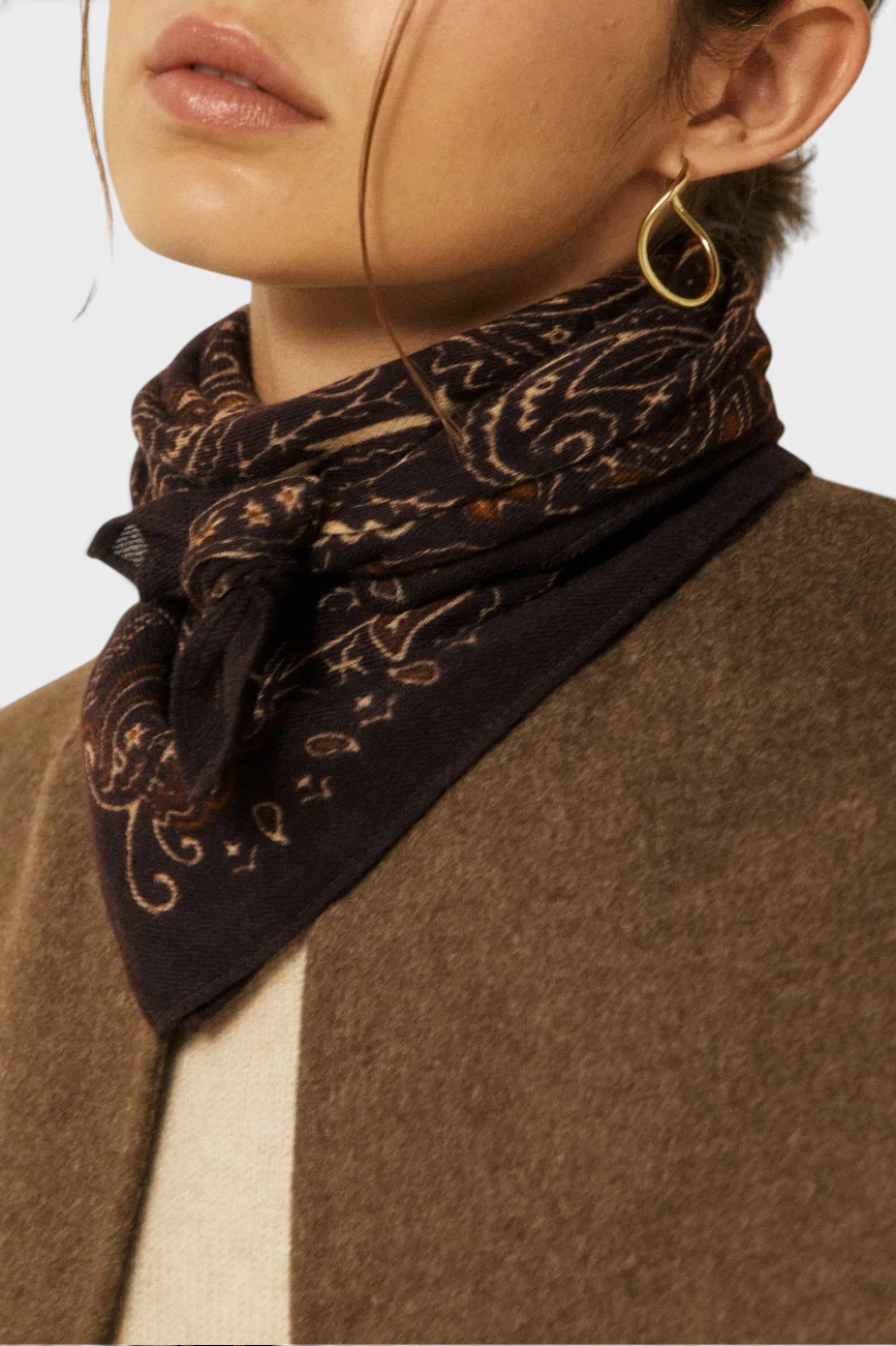The Copper Shed paisley bandana in dark brown wool worn around a model's neck with a brown coat.
