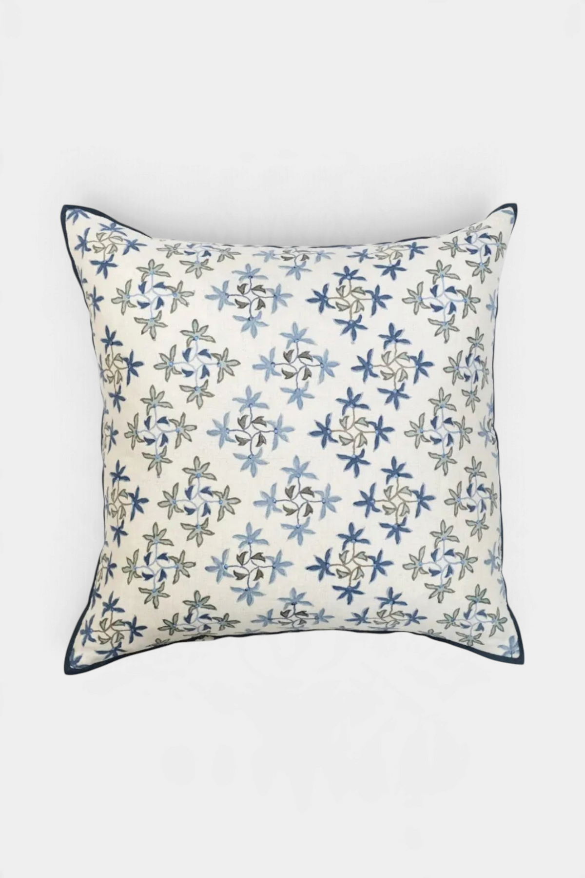The Copper Shed Celeste square throw pillow with a blue and grey floral ombre embroidery pattern on a white base.