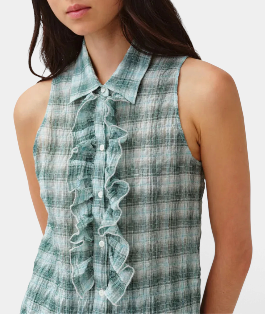 The Copper Shed Cheka Chemise sleeveless shirt in green plaid cotton with a ruffled jabot and button-front closure.