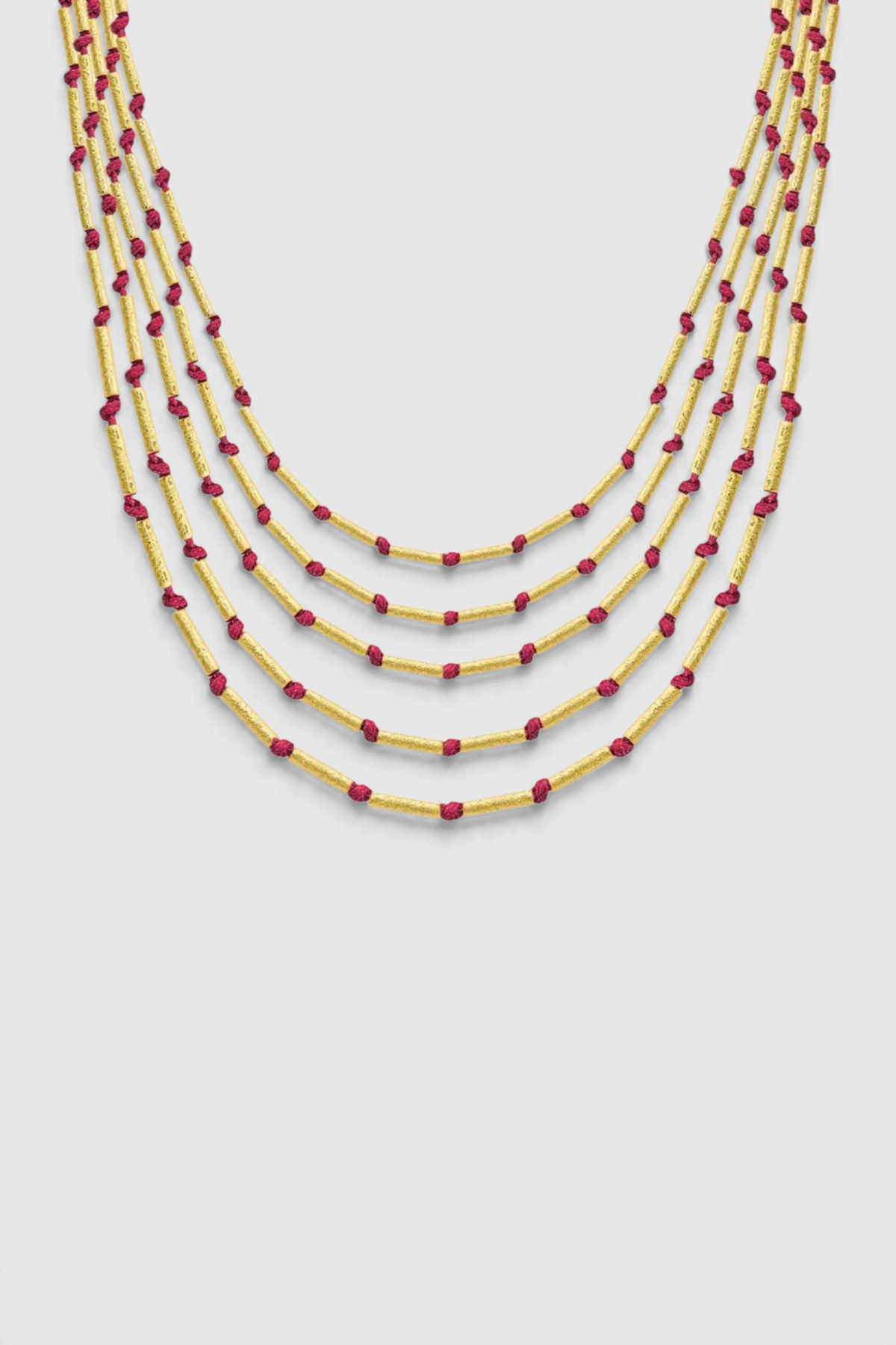 The Copper Shed Devitra multi-strand necklace featuring 18k gold plated cylinder beads and red string accents.