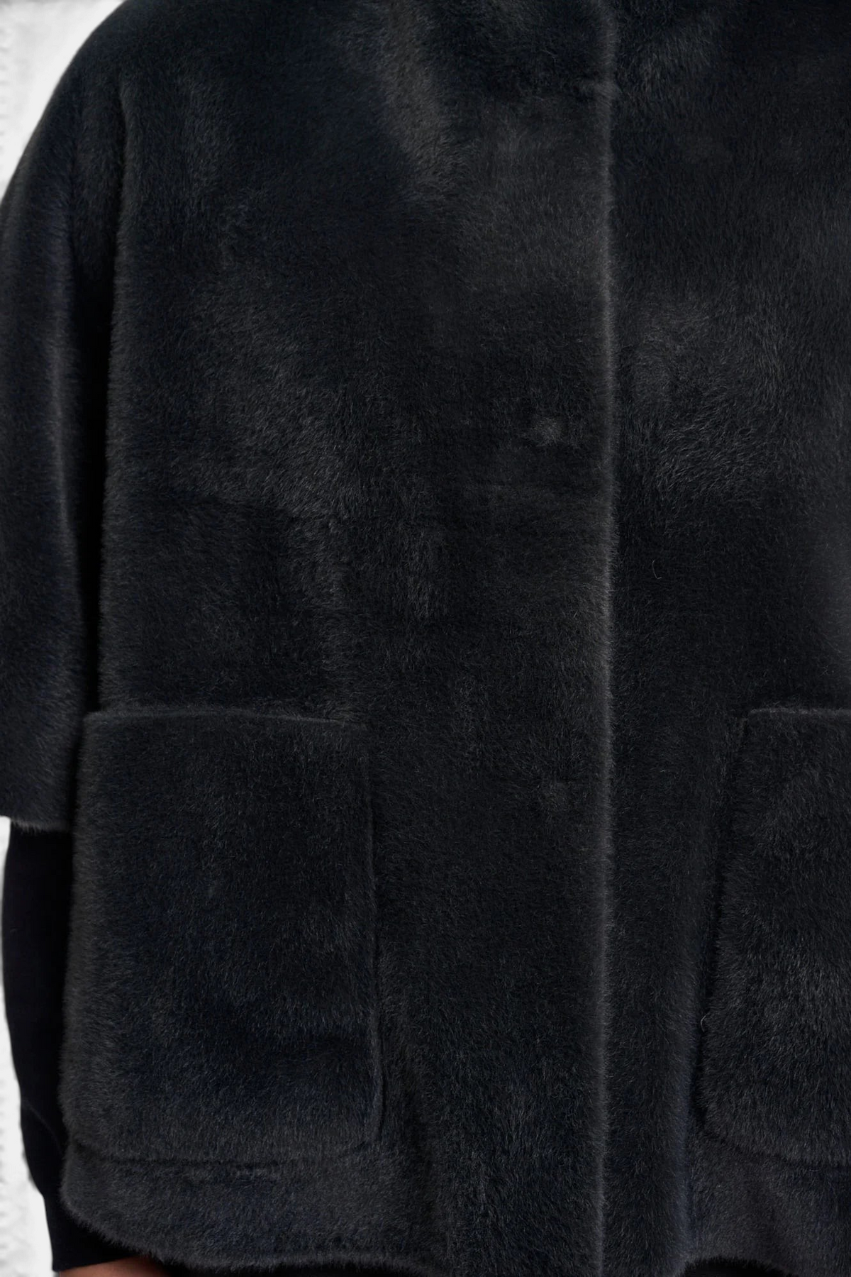 The Copper Shed Dewi cape in black faux fur with front patch pockets and button closure