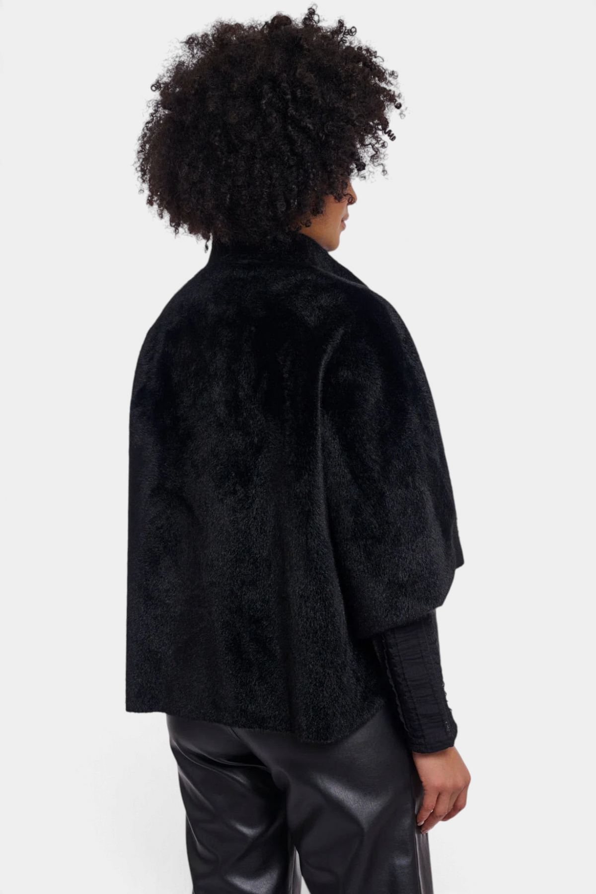 The Copper Shed Dewi black faux fur cape with a relaxed silhouette worn by a model against a white background