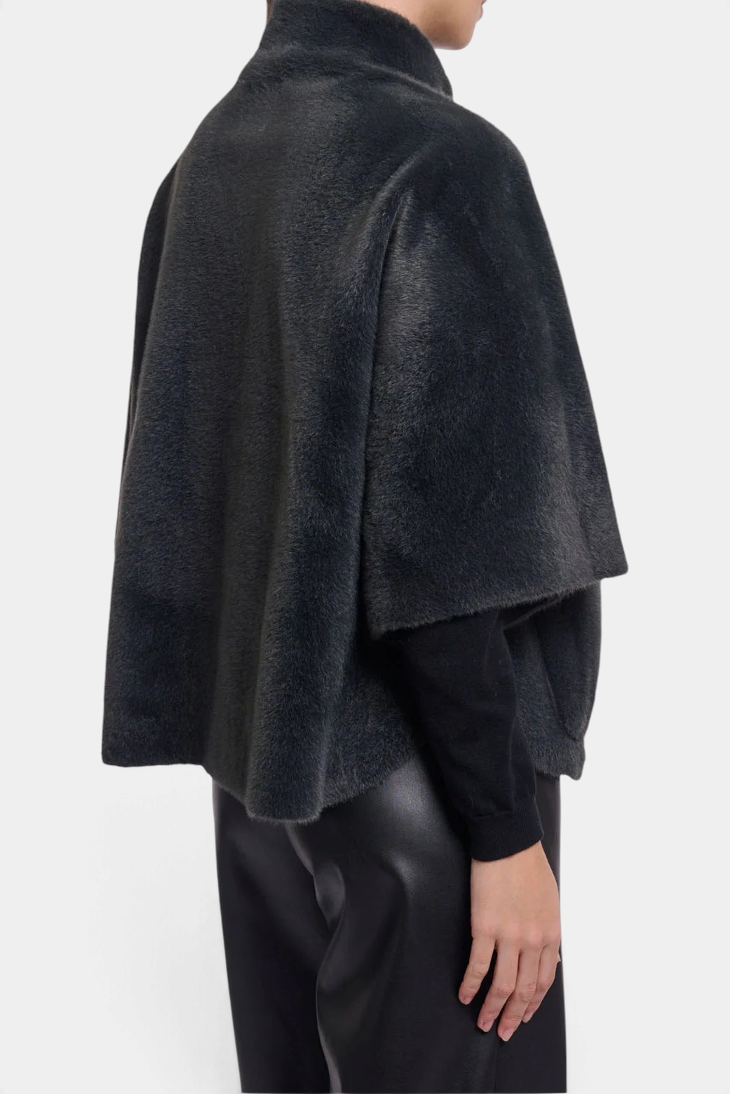 The Copper Shed Dewi cape in dark grey faux fur with a relaxed silhouette and short sleeves, worn over black layers.
