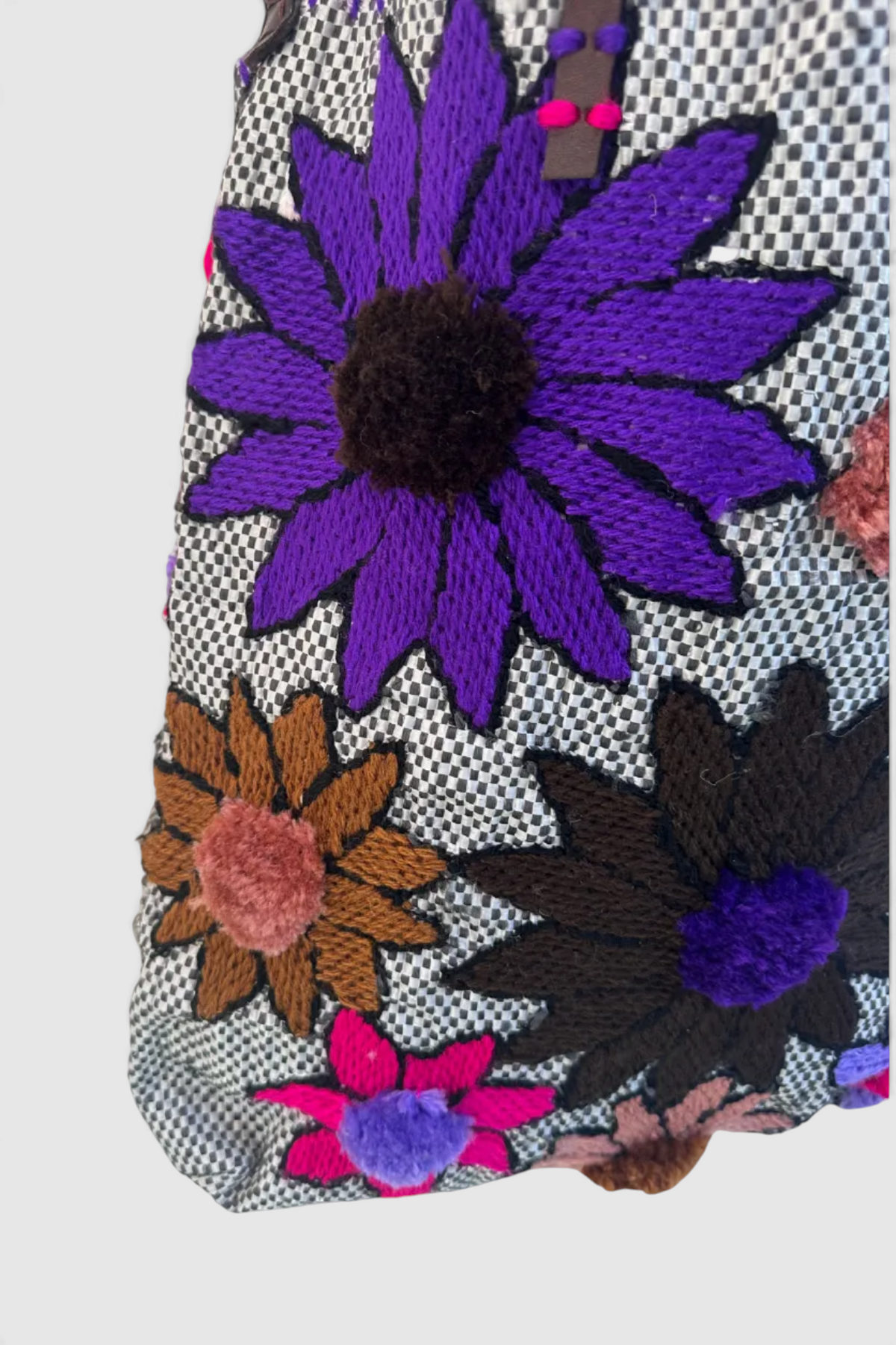 The Copper Shed En Shallah bag featuring black and white checkered fabric with vibrant embroidered floral patterns.
