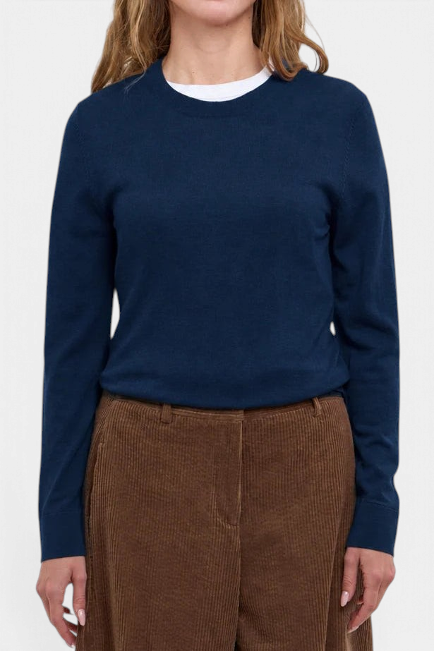 The Copper Shed Evan crewneck sweater in dark navy merino wool worn by a woman with brown corduroy trousers