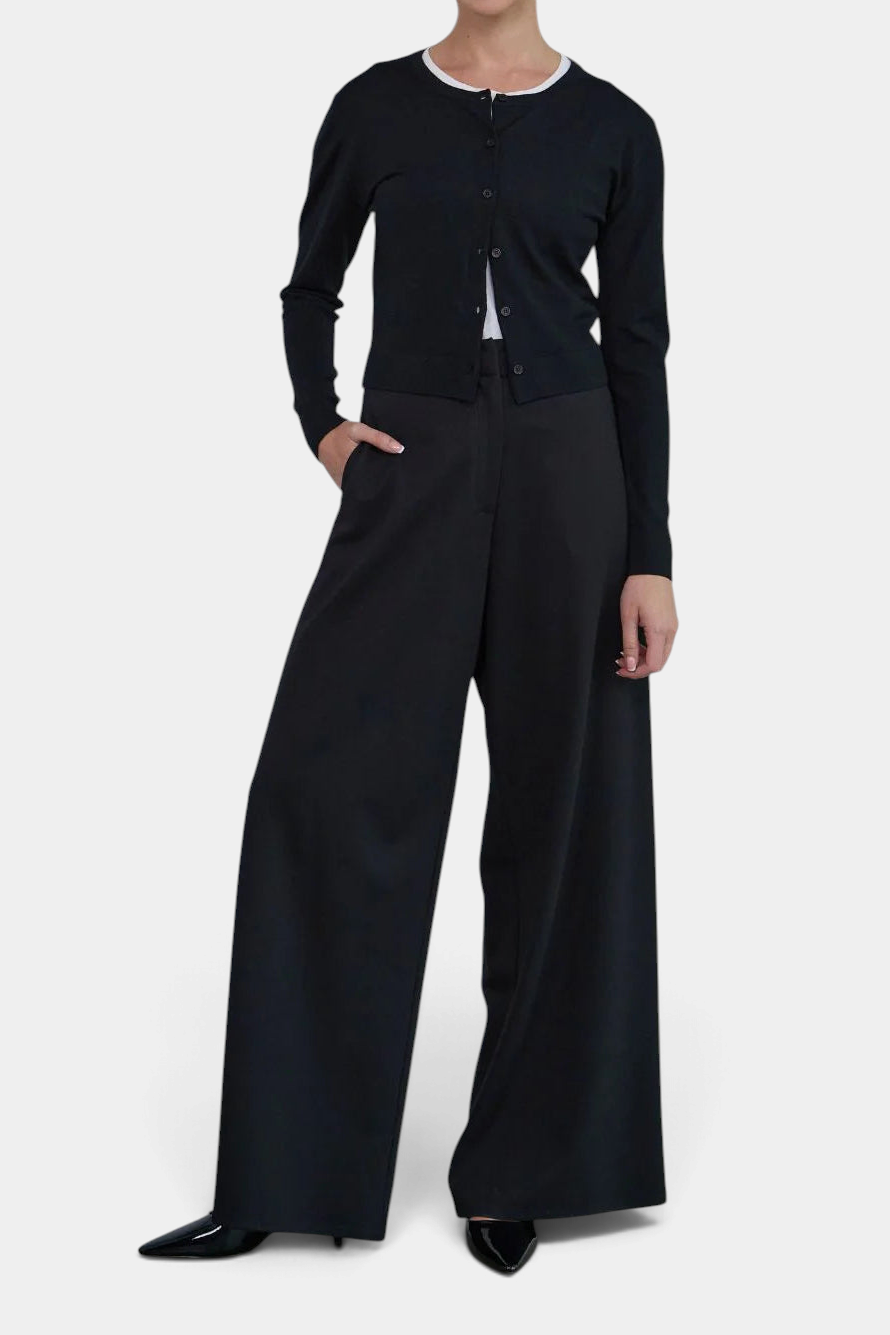 The Copper Shed Florence black cotton button-front cardigan with ribbed trims and shell buttons worn by a model.