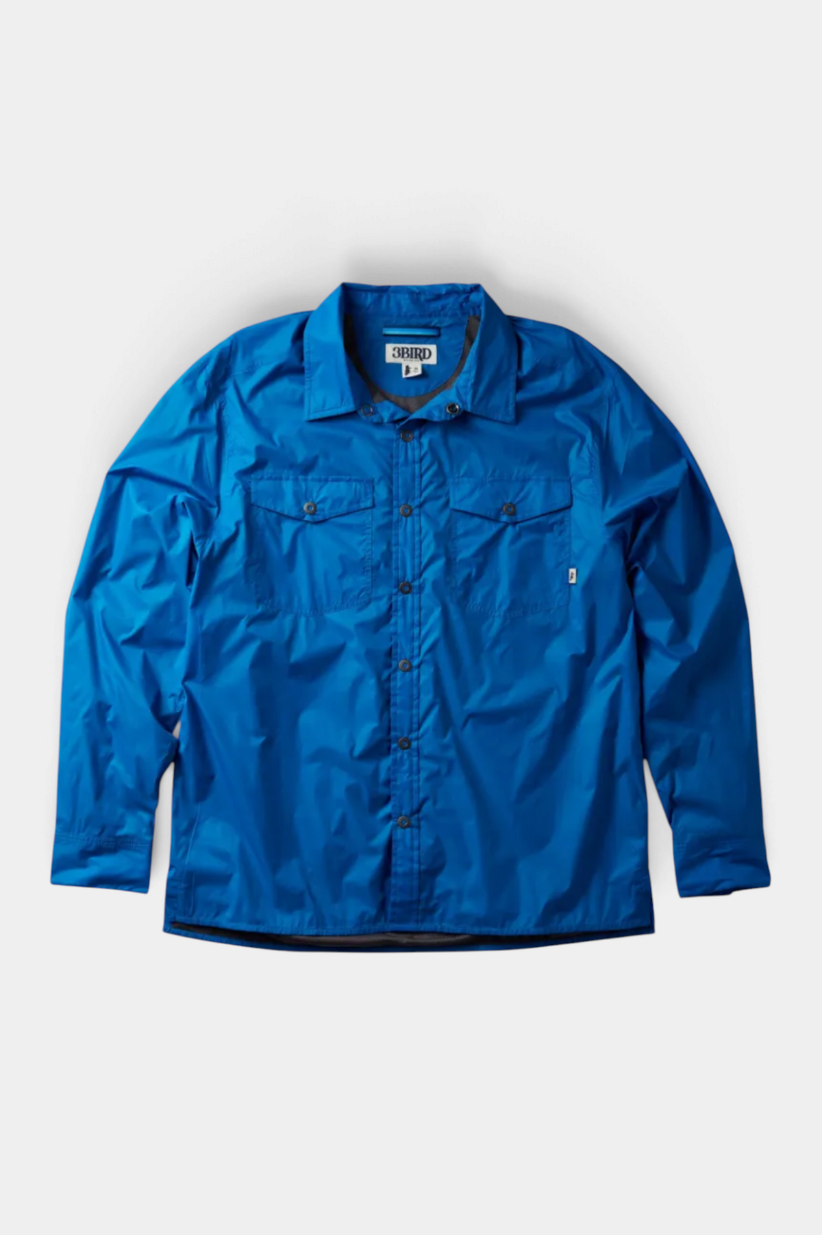 The Copper Shed Frigate Windshirt in bright blue, a lightweight technical button-down with dual chest pockets.